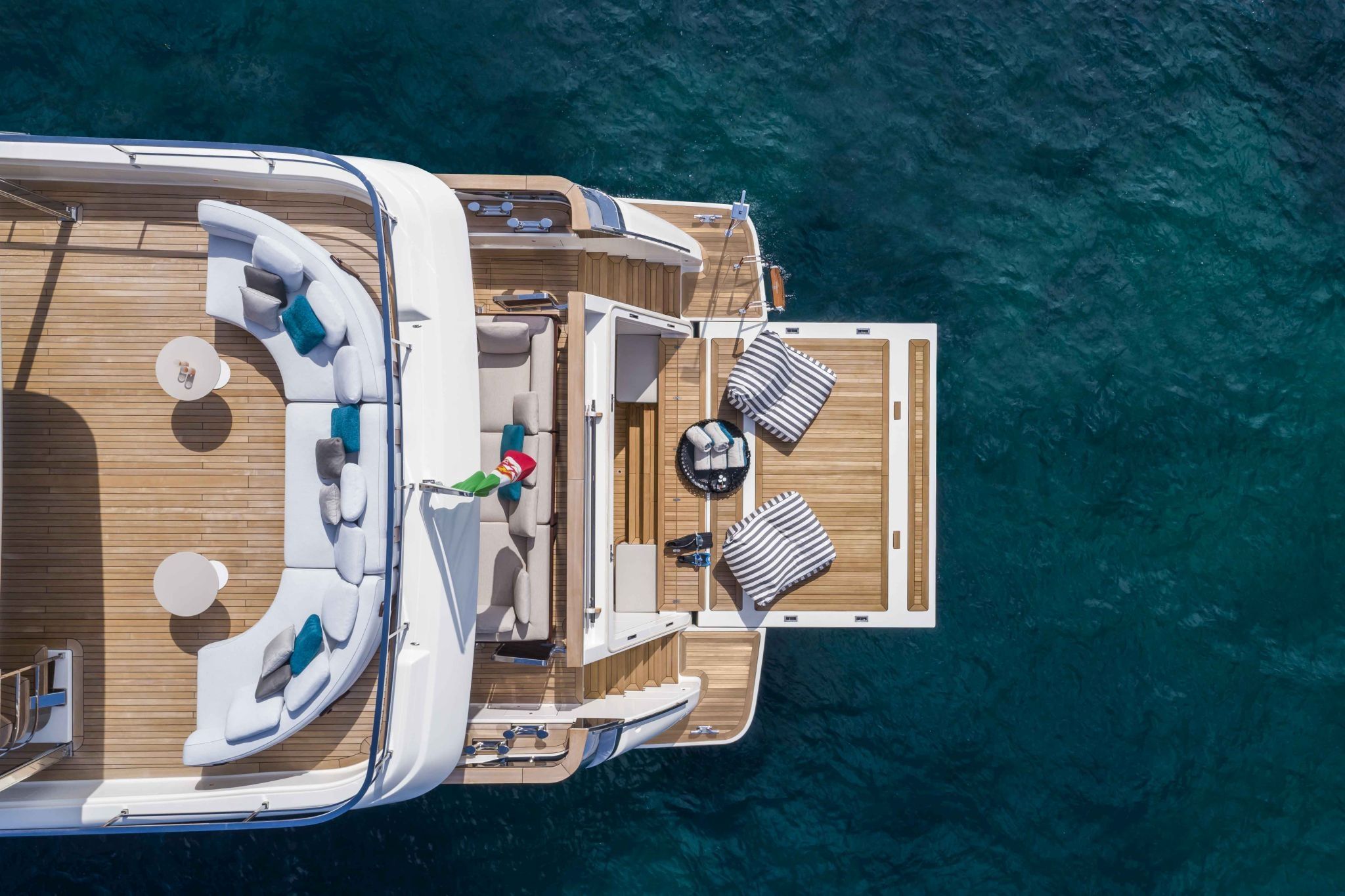 Aerial view of the Custom Line Navetta 42's aft deck with dining setup and sun loungers on teak decking.