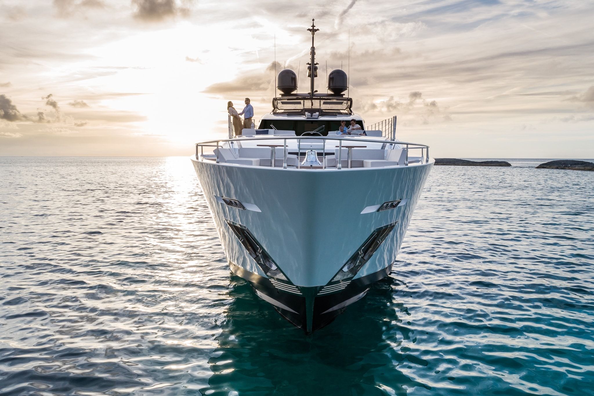 A man and woman standing on a majestic, white Custom Line yacht moored on the calm waters.