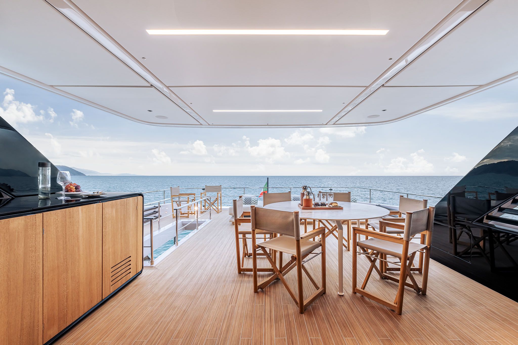 Elegant outdoor dining area on a luxury Ferretti yacht, featuring a wooden table and ocean views.