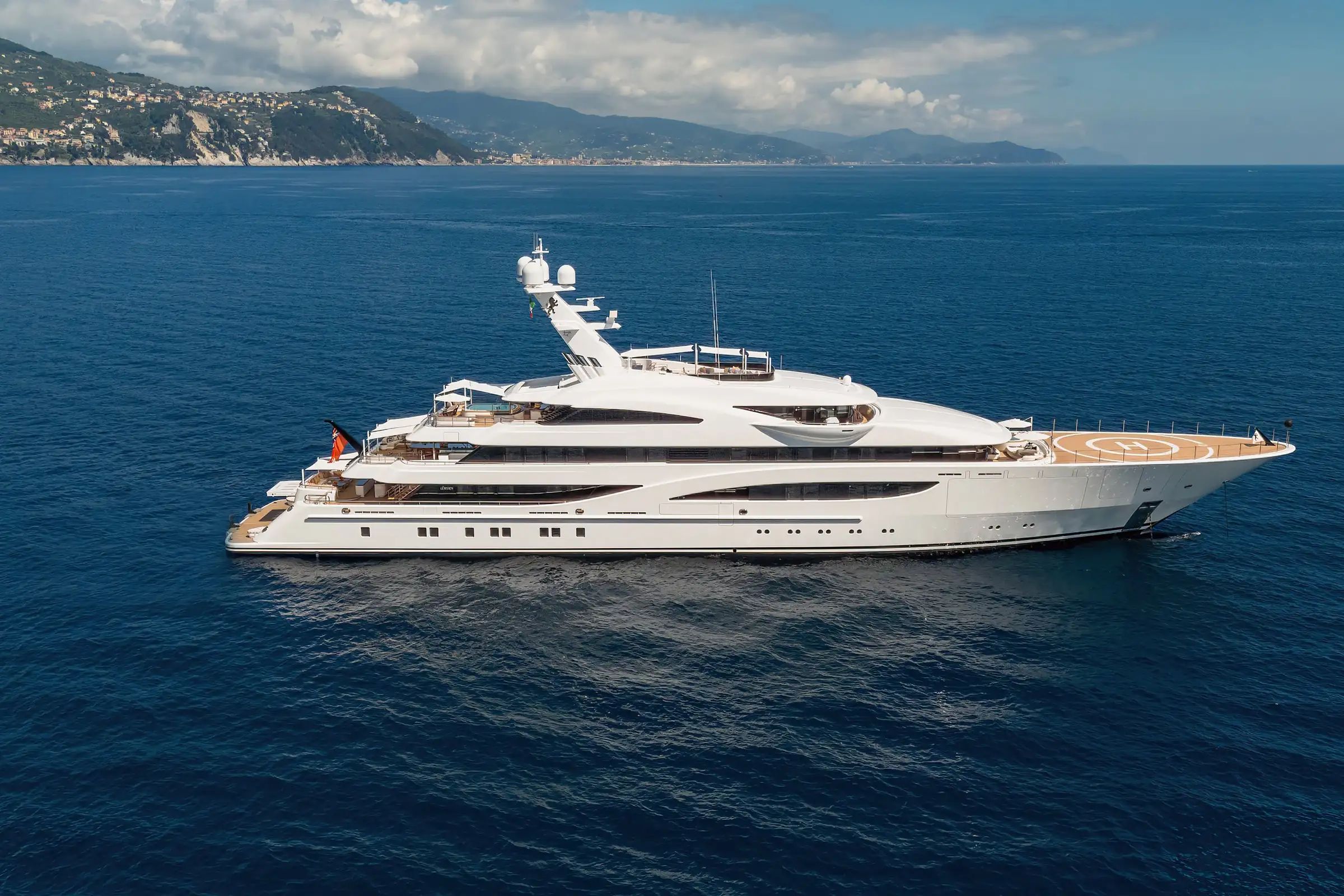 From Lurssen-Werft, Gigia, a white superyacht with helipad cruising on the sea on a bright day.