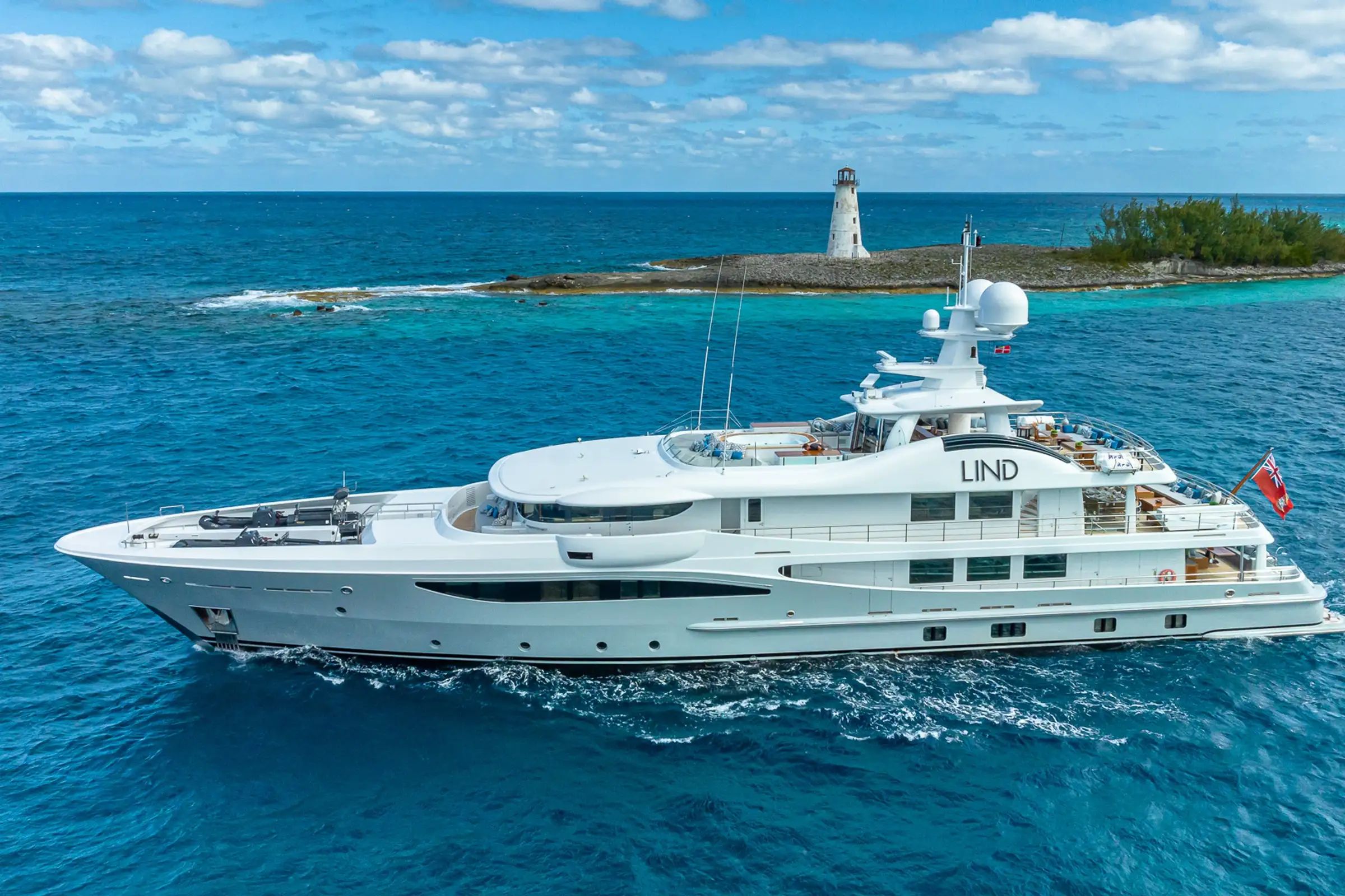 A massive, white luxury yacht Lind, showcasing its beauty while sailing on the vast blue sea on a bright day.