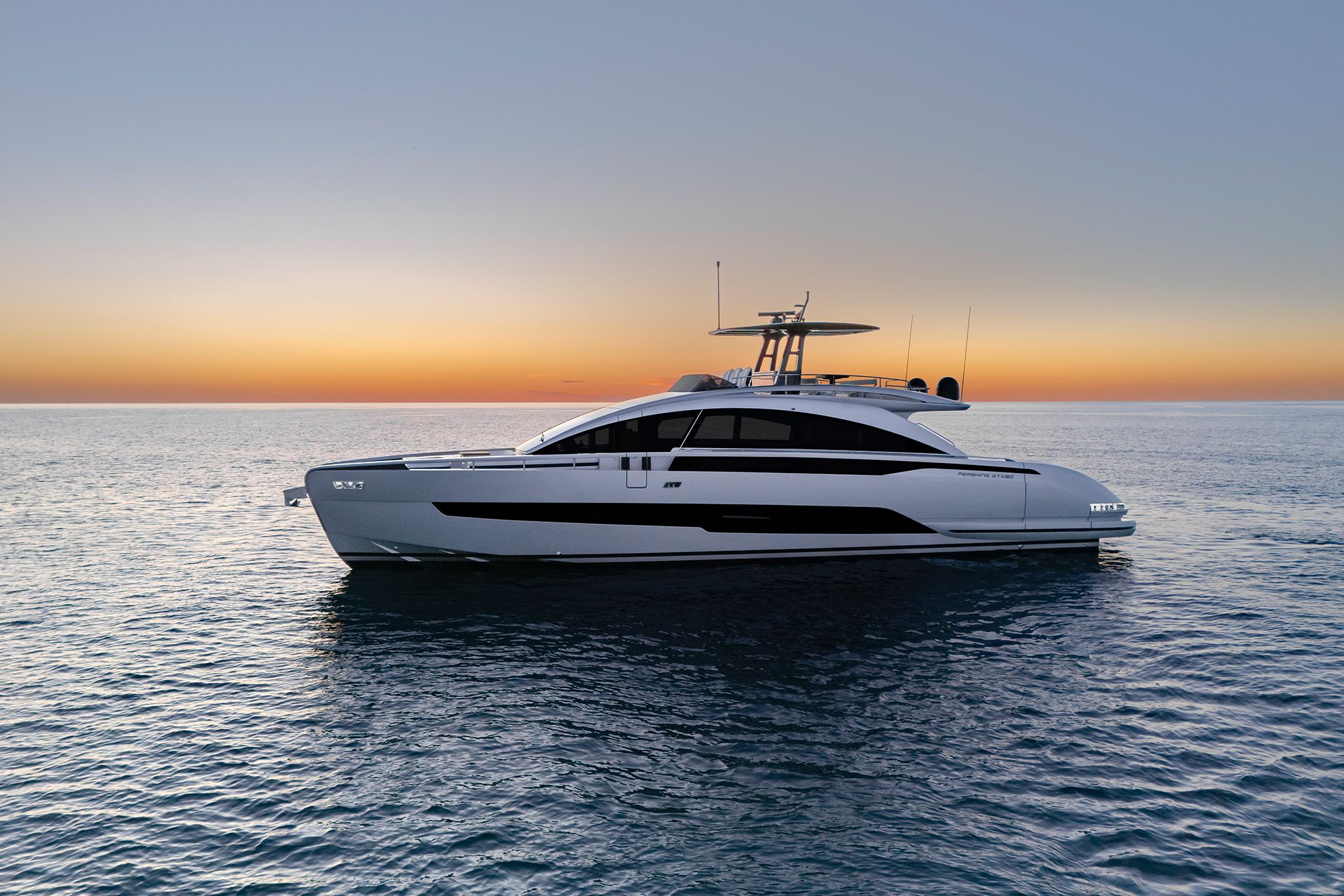Pershing Yacht: A lavish white Pershing GTX80 floating on the sea under a sunset.