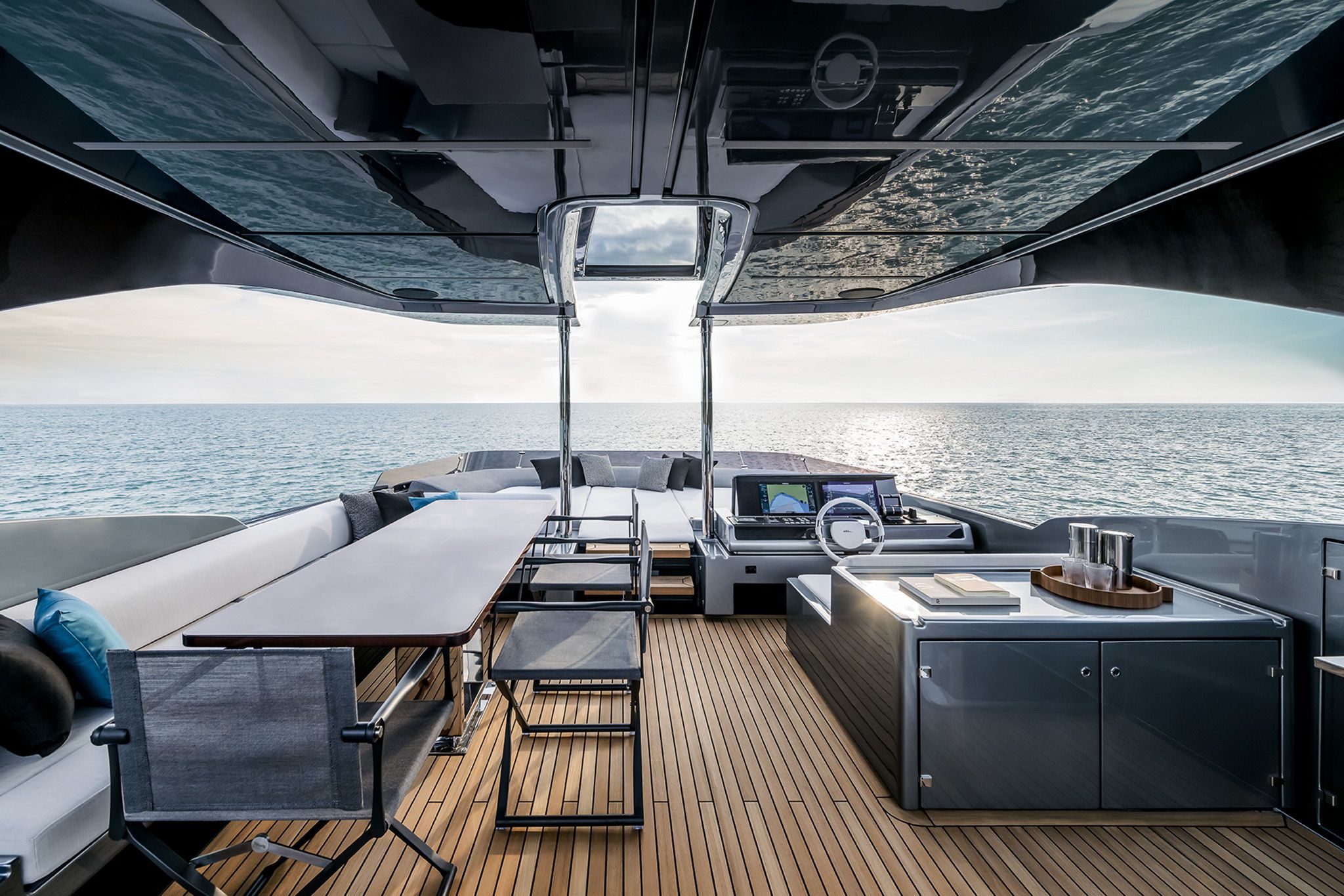 The flybridge yacht, Riva Diva 82 featuring seating, a dining area, and a view of the sea at sunset.