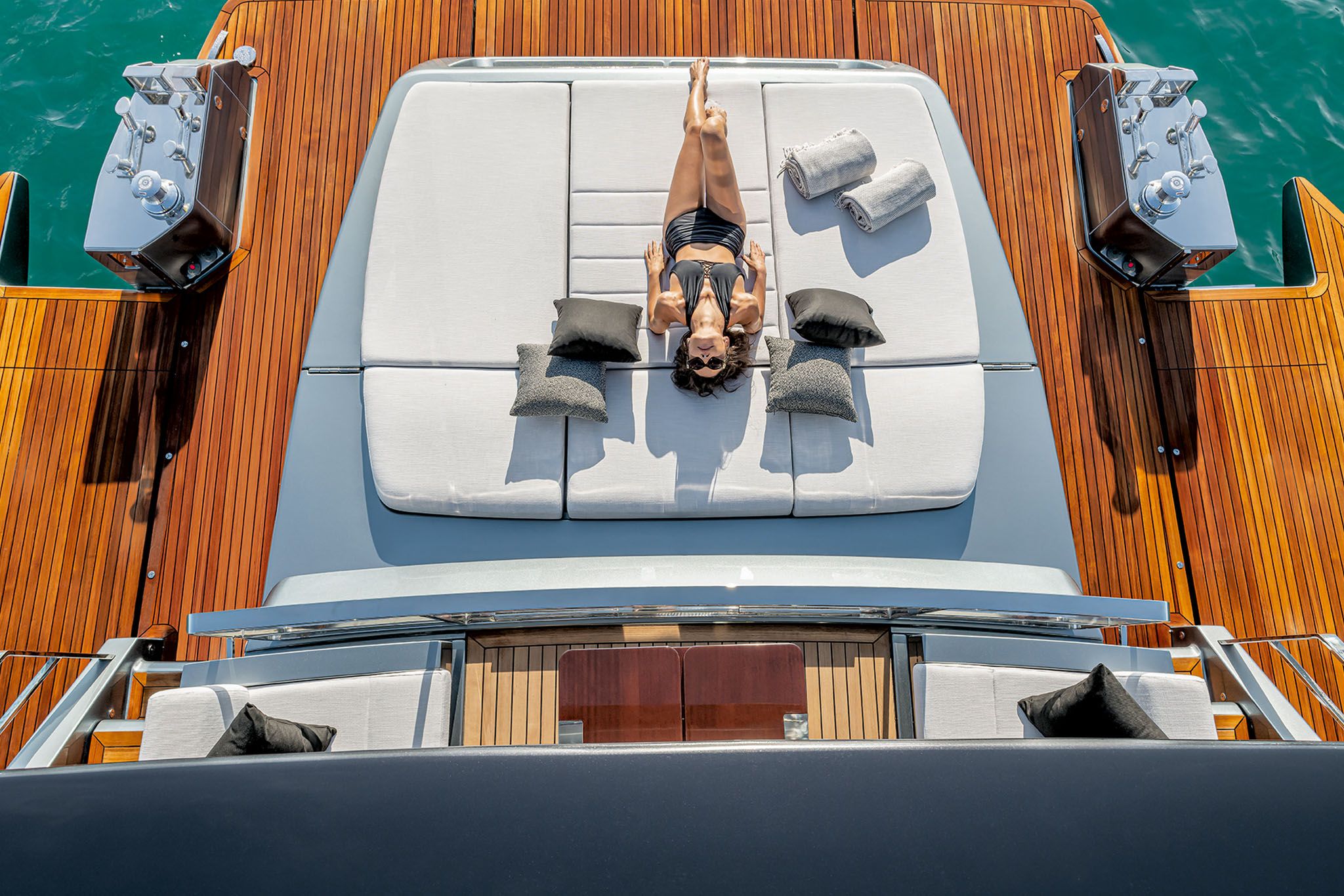 Starship yachts: A woman lies comfortably on the deck of Riva 82' Diva, basking in the sunlight surrounded by calm waters.