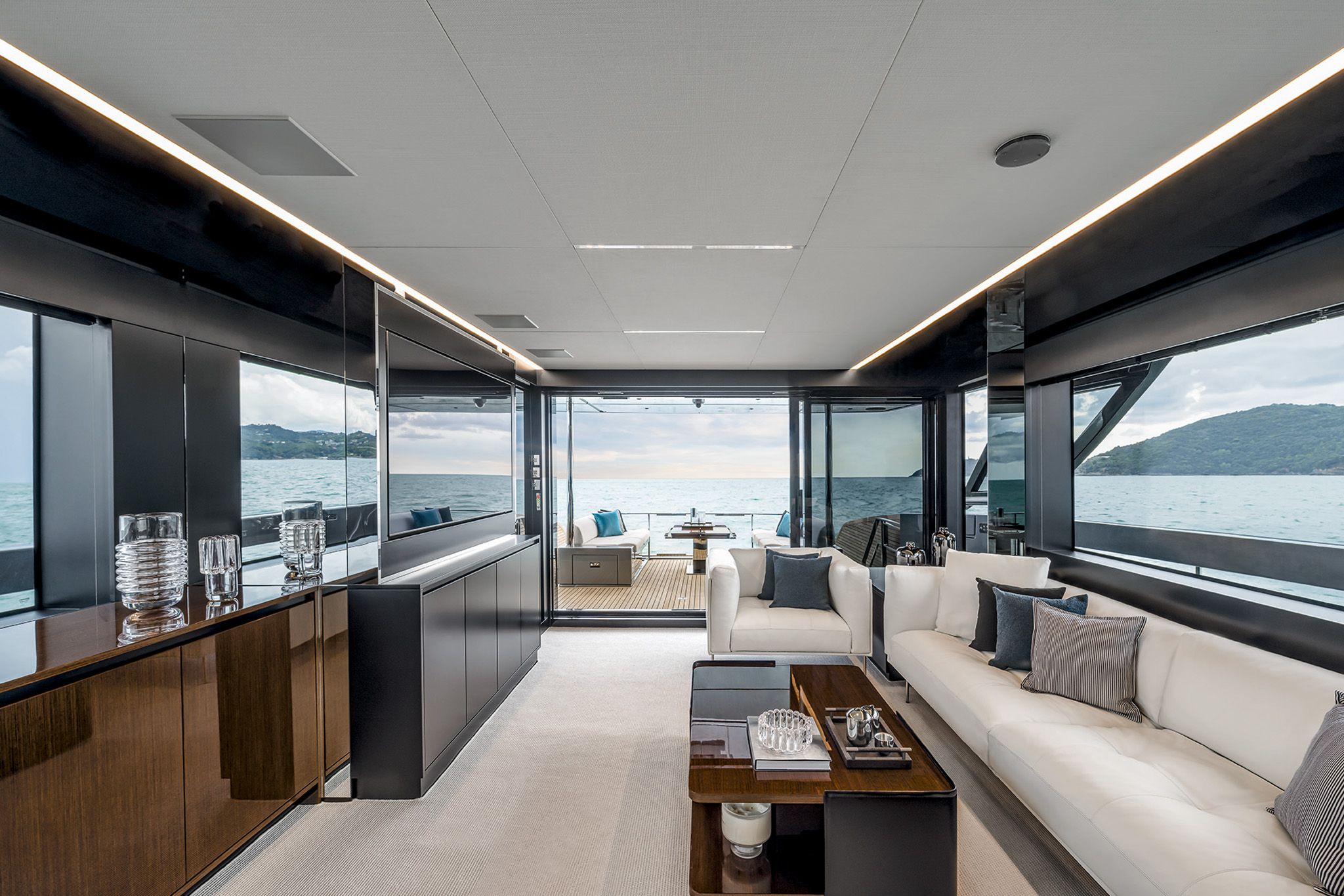 The luxury yacht interior of Riva Diva 82 with a lounge, large windows, with outdoor dining area.