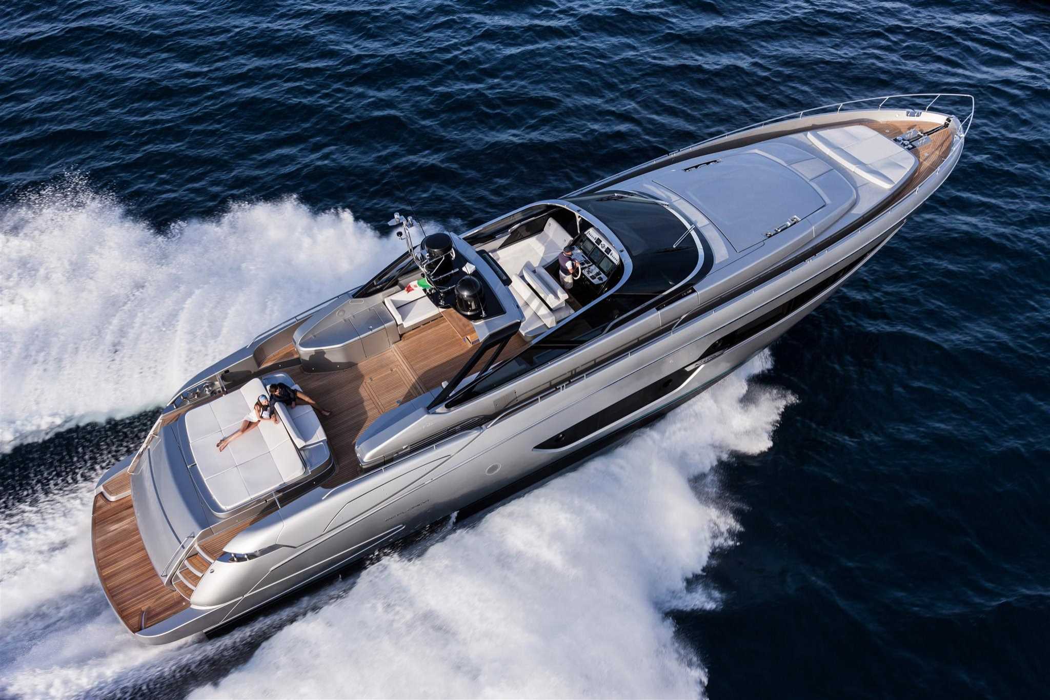 A man and woman on a speedy ride, a white and brown Riva yacht Florida 88, creating a trail of splashes in its wake.