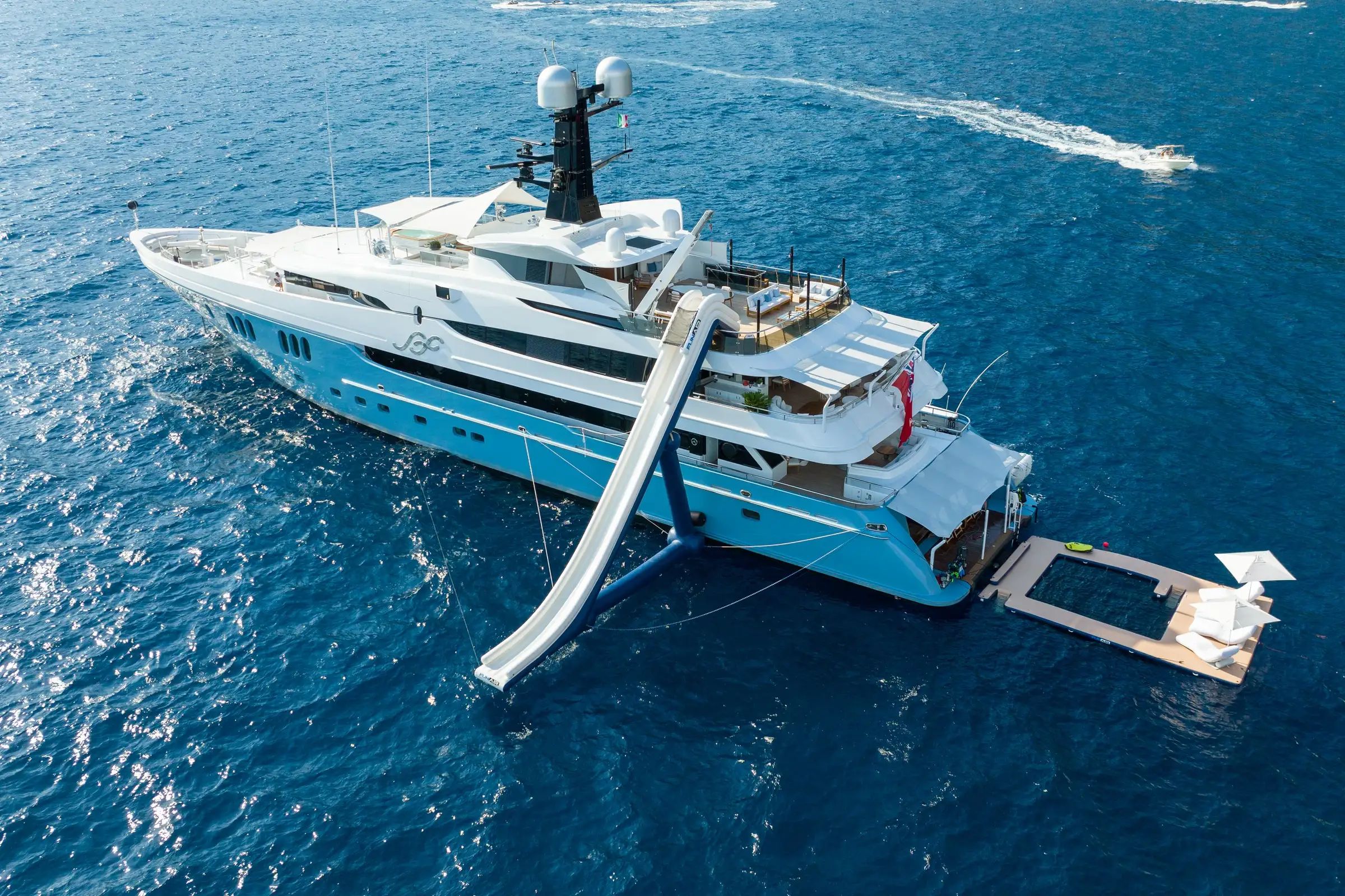 Superyacht SCOTT FREE with a light blue hull and white superstructure, featuring a water slide on the calm deep blue sea.