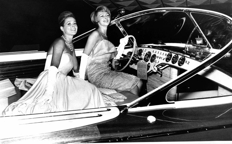 Two women on the Aquarama Super yacht’s polished wooden deck, with iconic logo, showcasing timeless luxury and craftsmanship.
