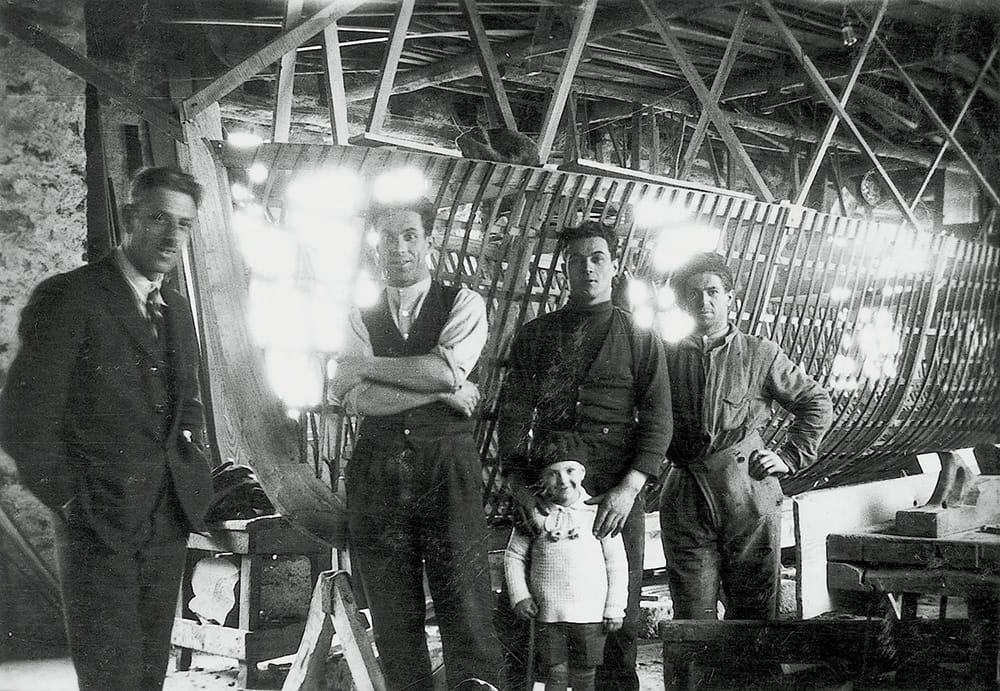 Historic photo of Cranchi boatbuilders - four adults and one child in a workshop, capturing the early craftsmanship of Cranchi.