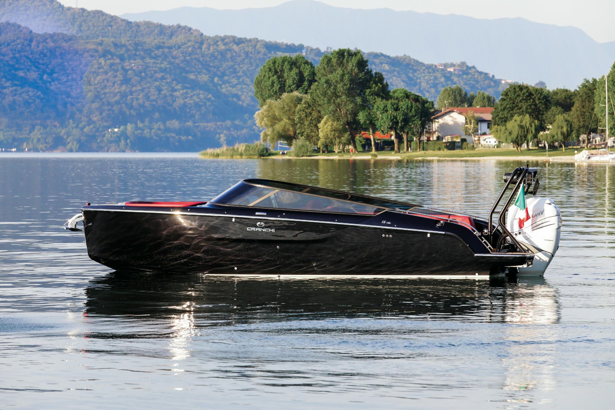 A classy, stylish black E26 Rider Cranchi Yachts floating on the water by the mountains.