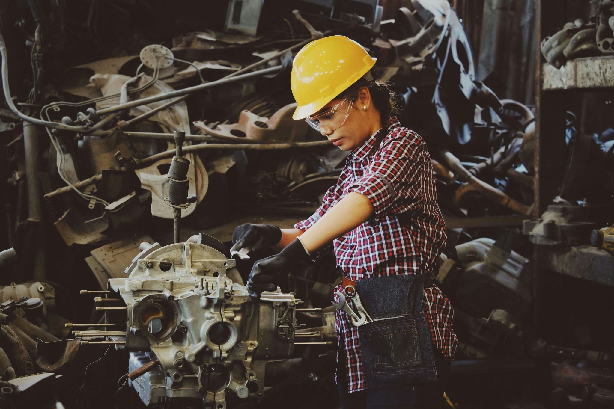 A woman wearing a yellow safety helmet, performing maintenance on some machinery.