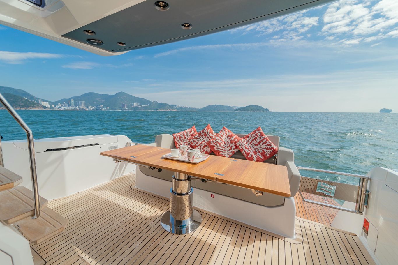 Aft dining on Ferretti Yachts 500 with teak floor, polished table, and custom cushions facing ocean views