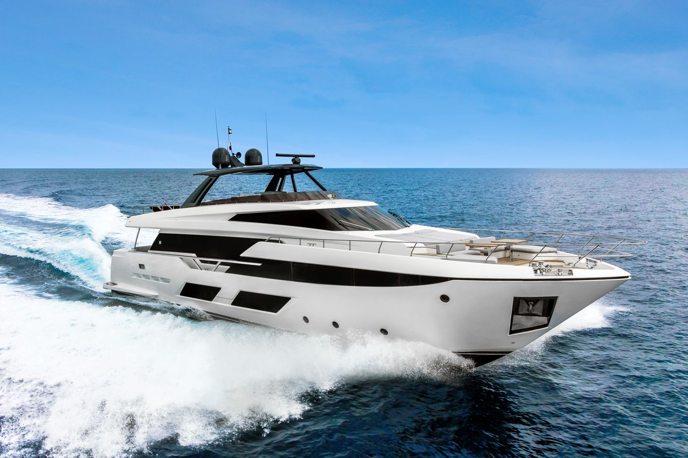 A magnificent white Ferretti Yachts 920 cruising through the ocean waves under a bright blue sky.