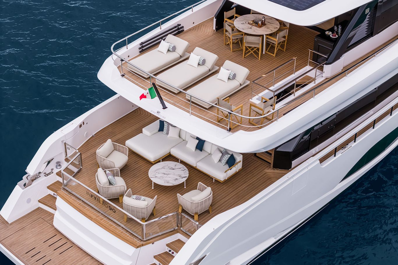 Aft deck of the Infynito 90 yacht with luxurious seating, sun loungers, and a dining area.