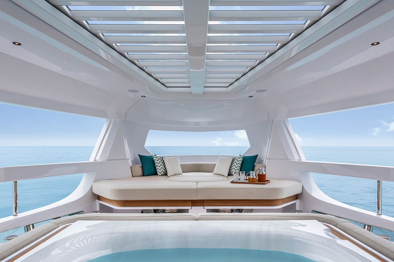 Luxurious lounge area on a Ferretti Yachts Infynito 90 yacht, featuring cushioned seating, ocean views, and a retractable roof.