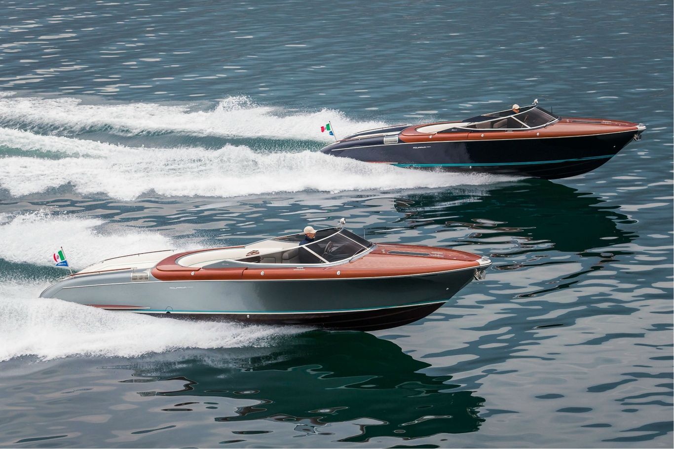Two men racing through the waters on a beautiful black and red Riva Aquariva 33 on tranquil waters.