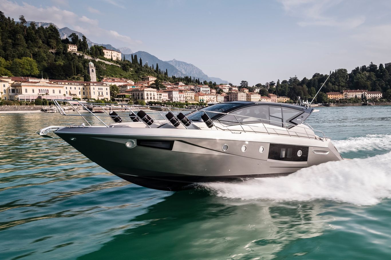 Cranchi Yacht: A modern Cranchi M44 HT cruising across the blue water near a cityscape.