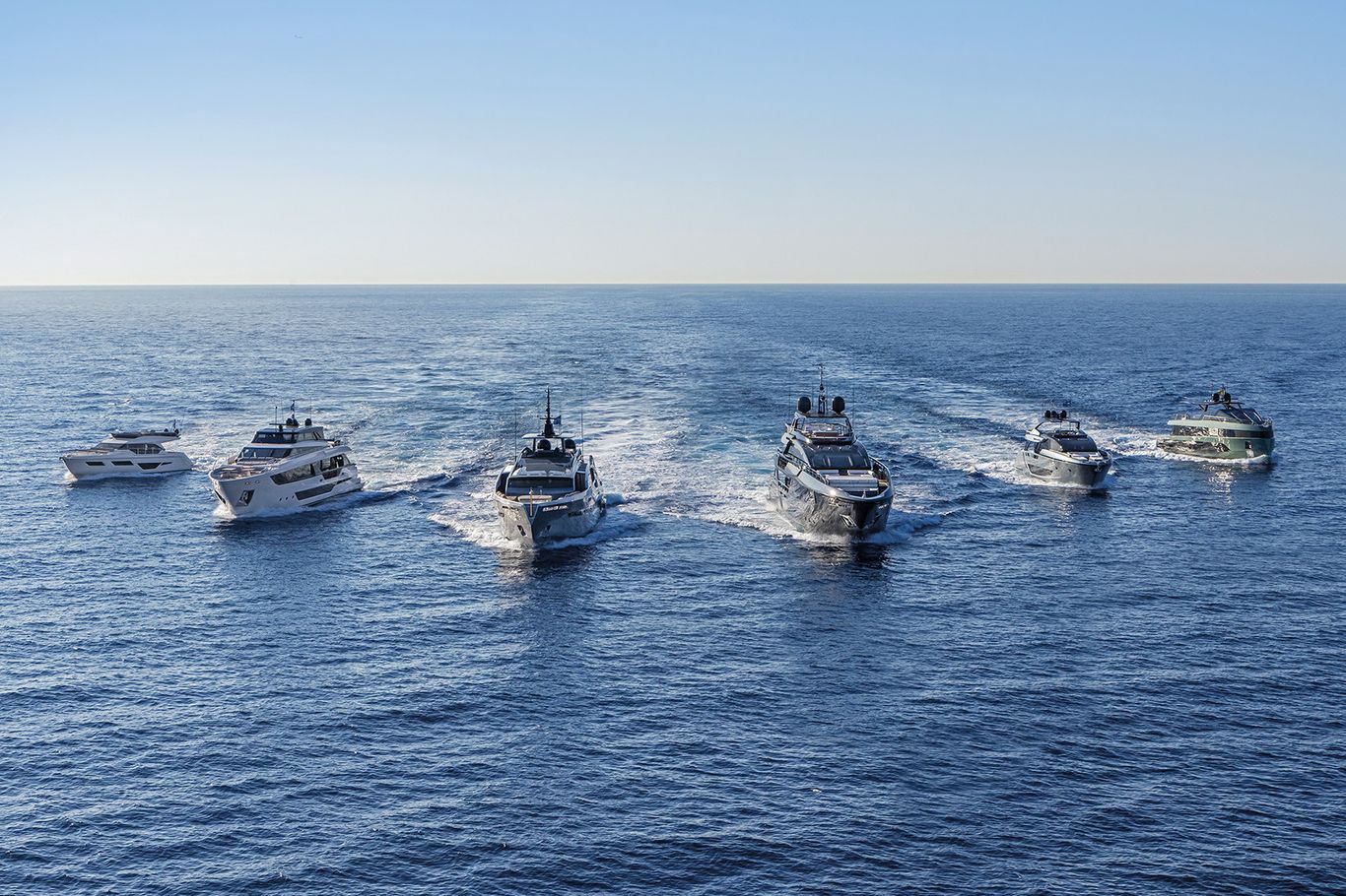 Six Ferretti yachts cruising in formation on the open sea, available through Starship Yachts.