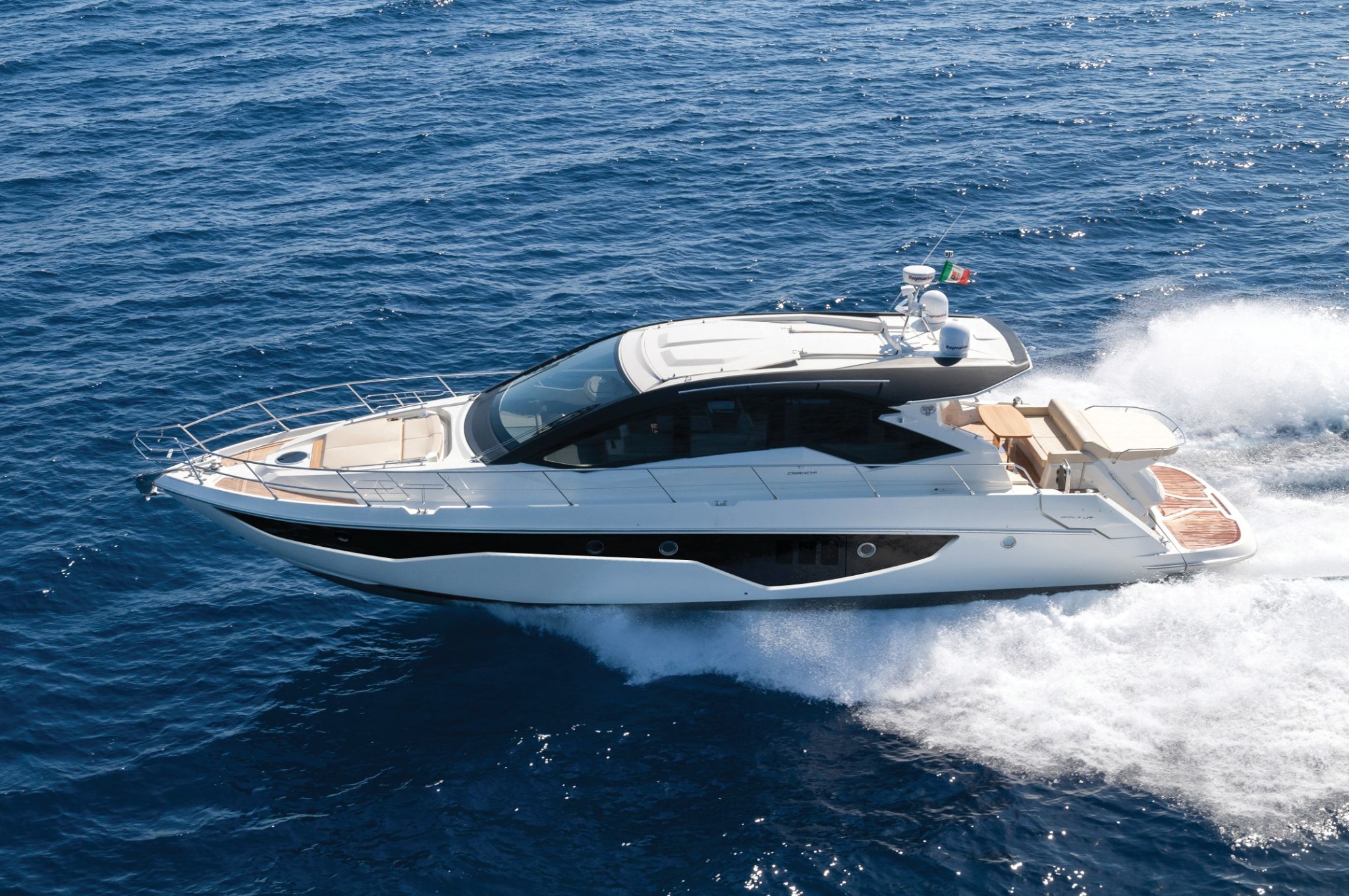 A stylish 60 HT by Cranchi Yachts speeding through the ocean creating waves on a bright day.