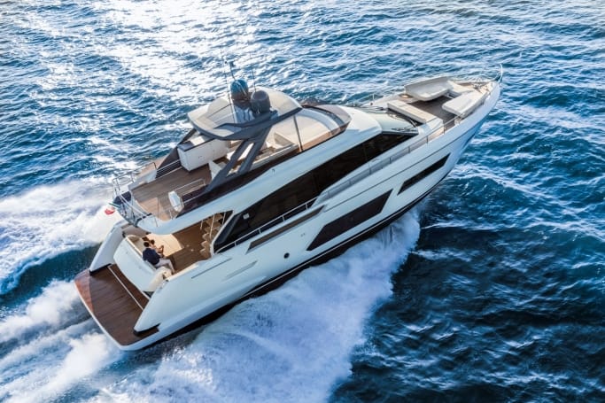 A stunning white Ferretti Yachts 670 showcasing elegance while cruising through the ocean waves on a bright day.