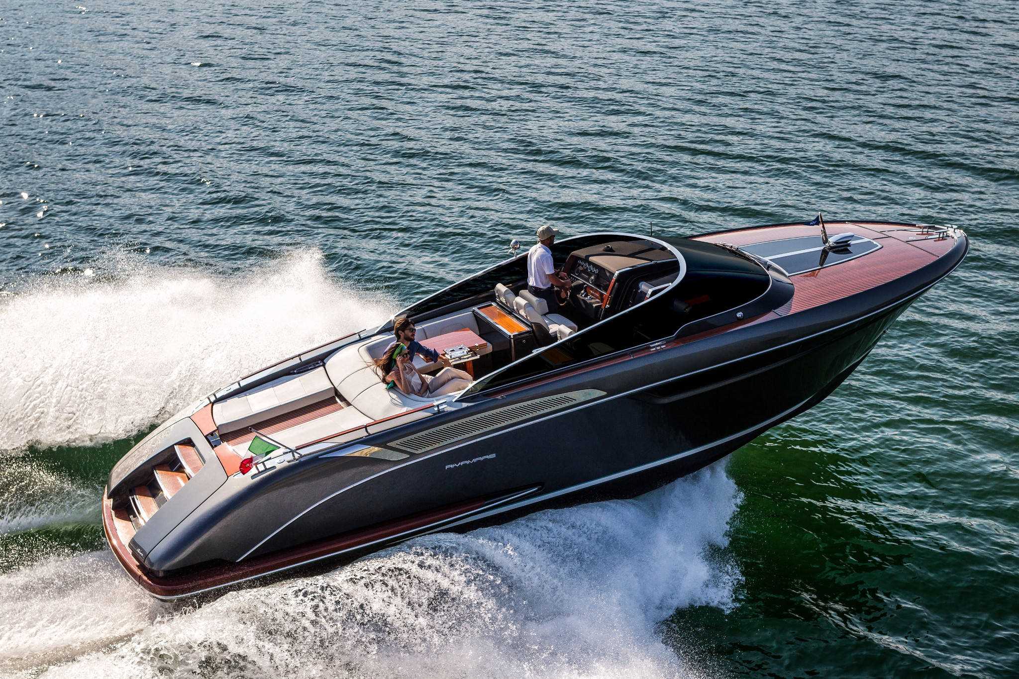 A sleek black and brown Rivamare by Riva speeding through the open waters on a bright day.