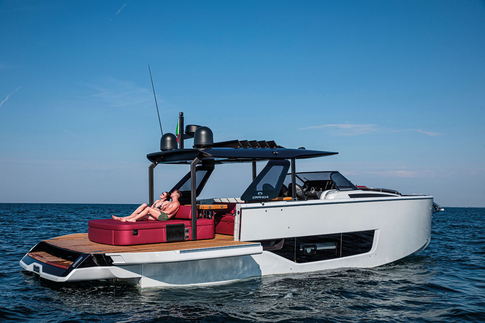 A man and woman relaxing on the rear of a uniquely structured A46 Luxury Tender from Cranchi on a sunny day.