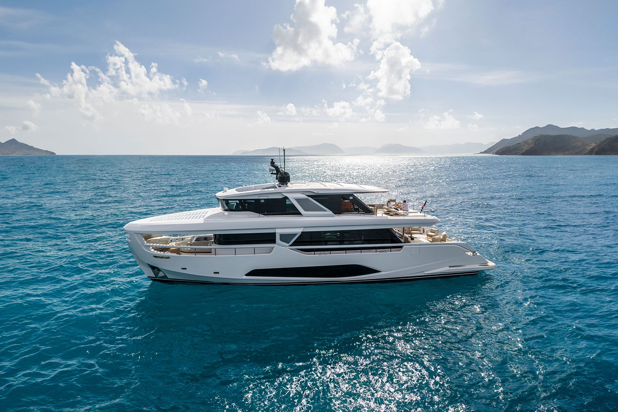 A white Infynito 90 yacht floating graciously on the deep blue water showcasing its elegant structure.