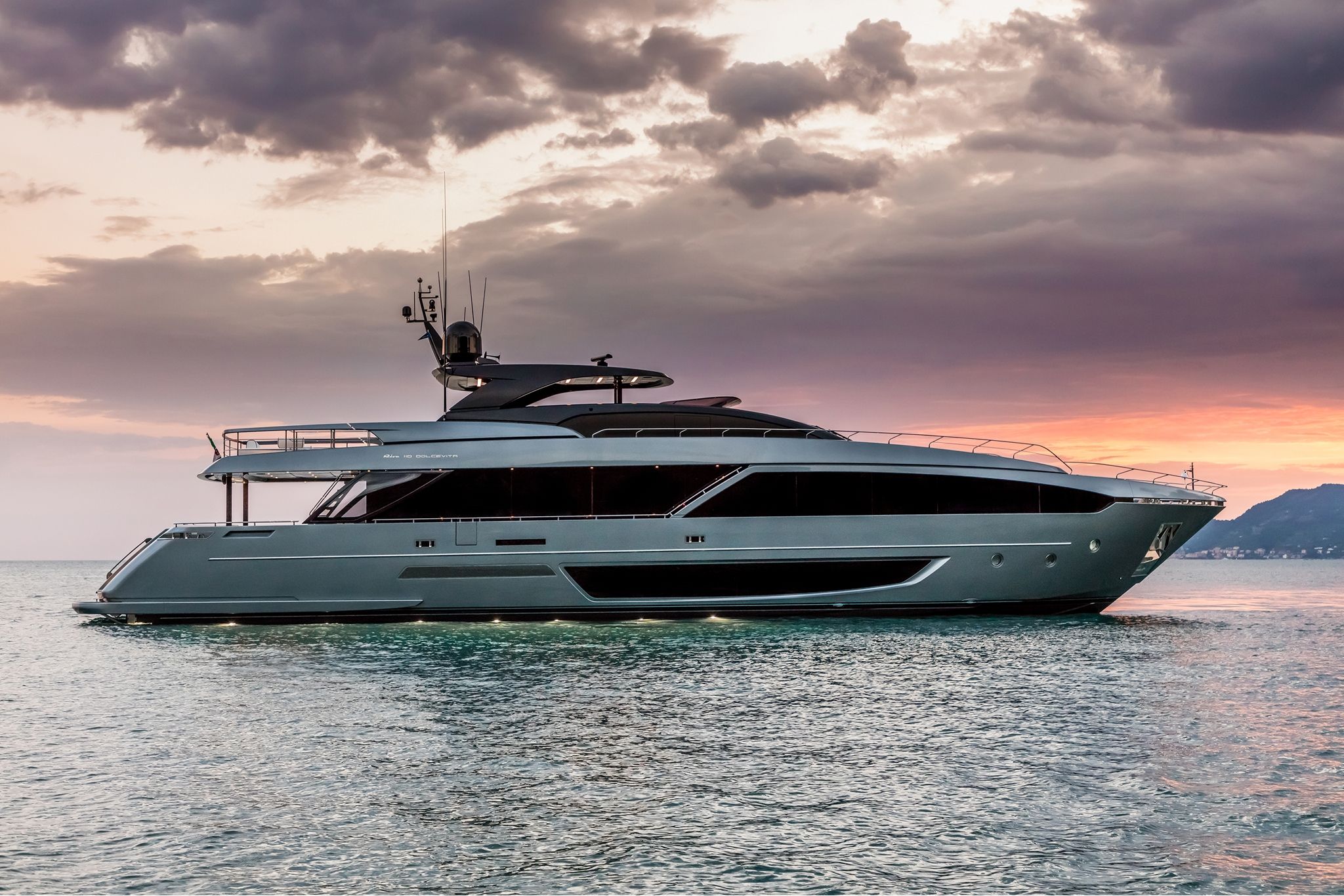 A grand 110'Dolcevita by Riva cruising on the open waters under a beautiful sunset.
