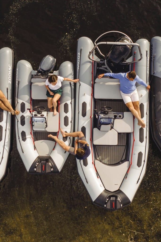 A group of individuals sitting leisurely on a line of the elegant Zodiac Open yacht tender on a sandy, brown sea.