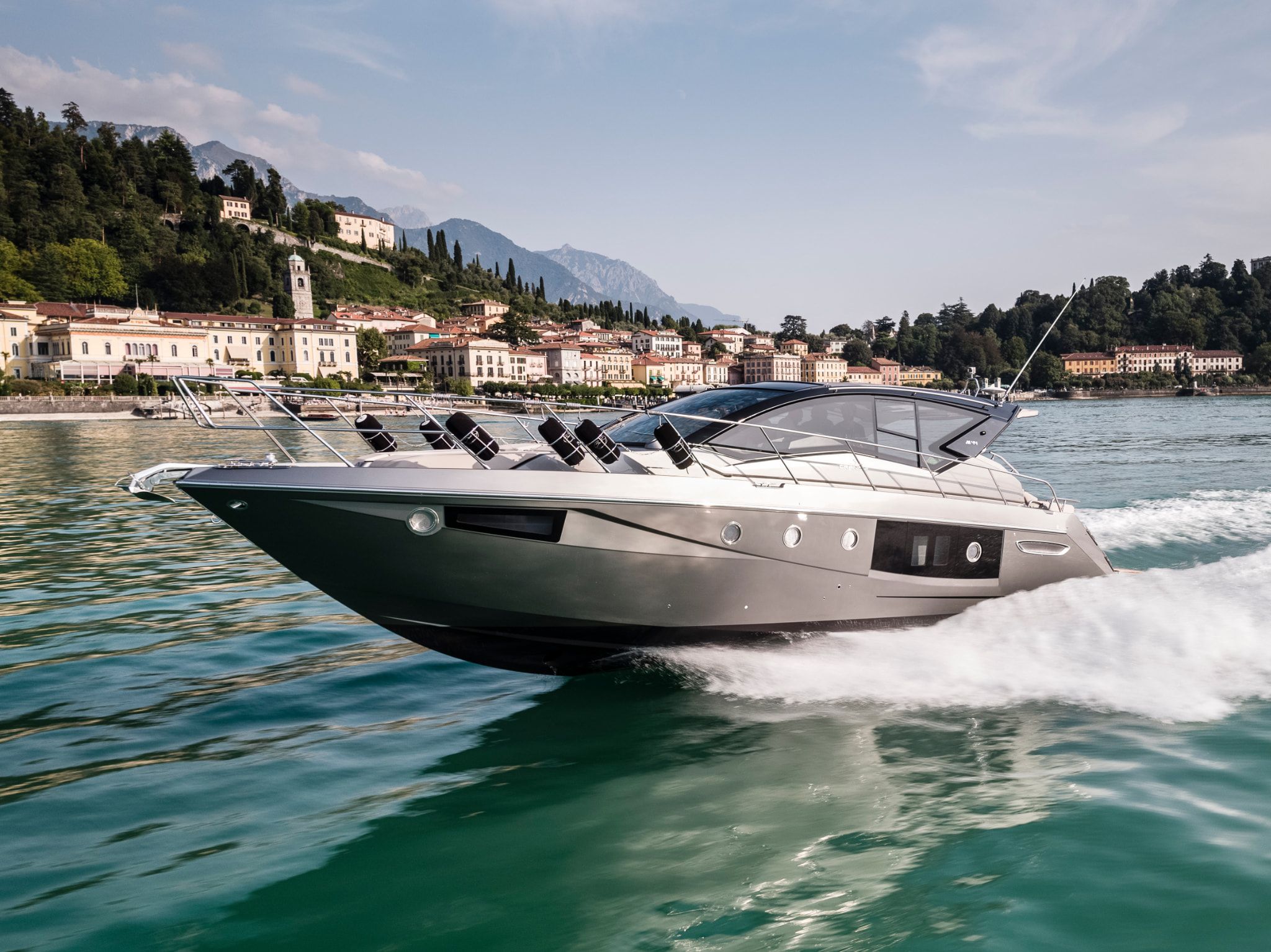 Cranchi Yacht: A modern Cranchi M44 HT cruising across the blue water near a cityscape.