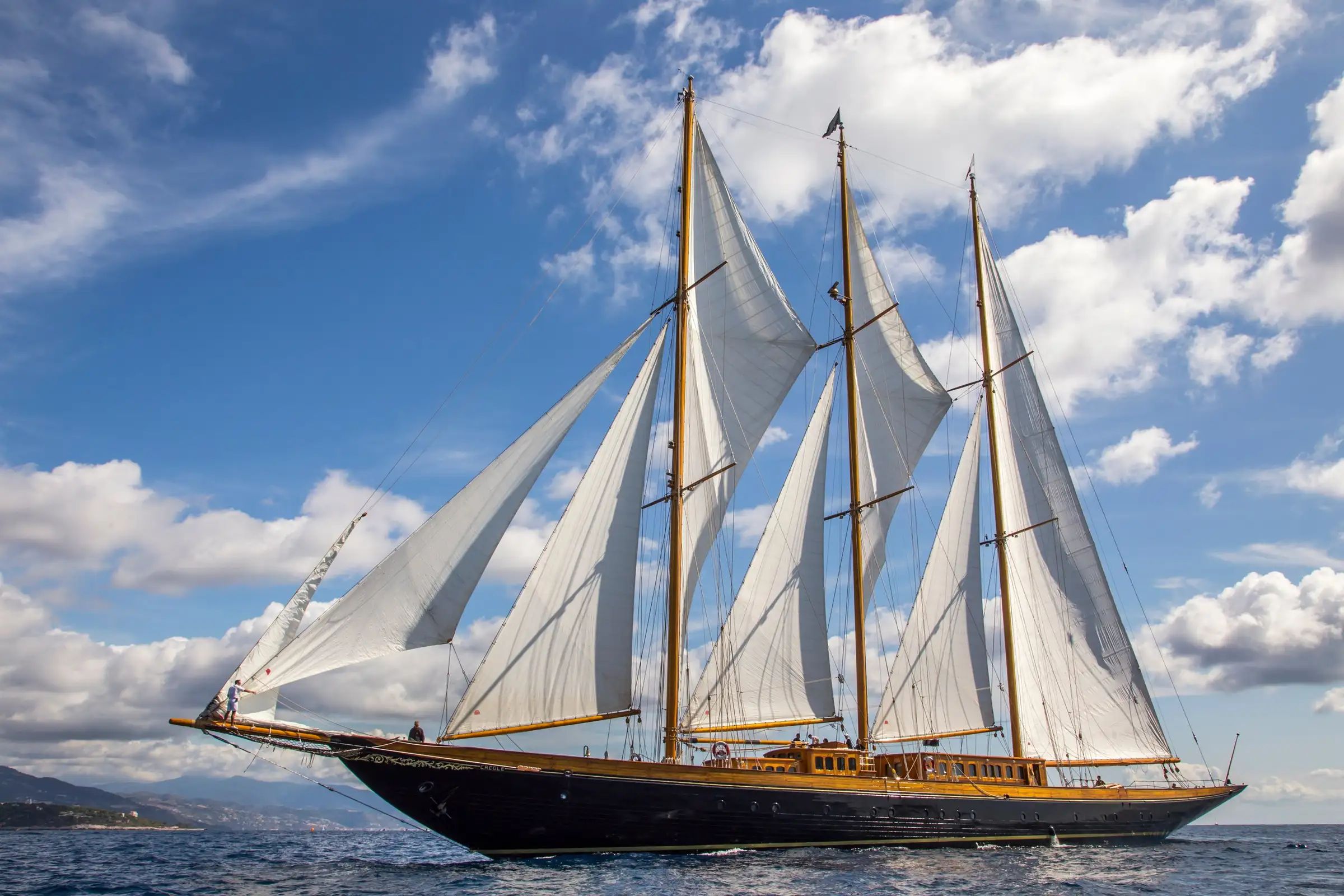 A white sailed, luxury yacht CREOLE, sailing on the ocean under a cloudy sky.