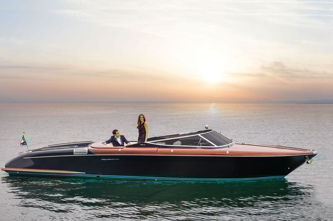 A man and woman leisurely hanging out on the Aquariva Super by Riva under a stunning sunset.