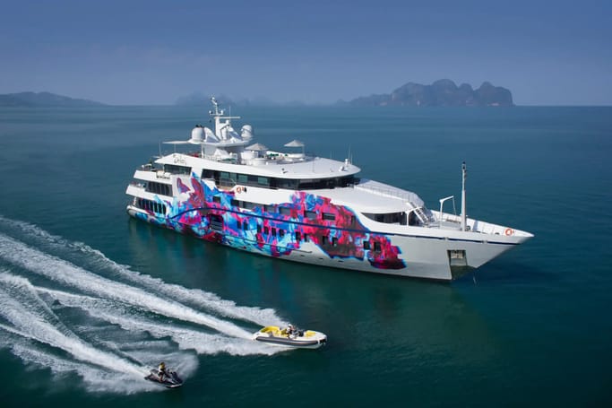 A large, white Superyacht Saluzi with a unique design on its body, cruising through the waters alongside two boats.