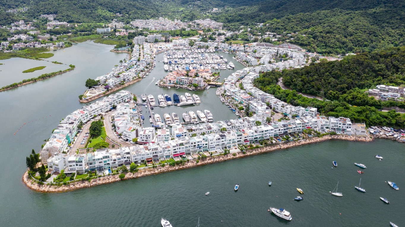 Aerial view of Club Marina Cove Hong Kong with boats docked along curving waterways surrounded by white buildings.