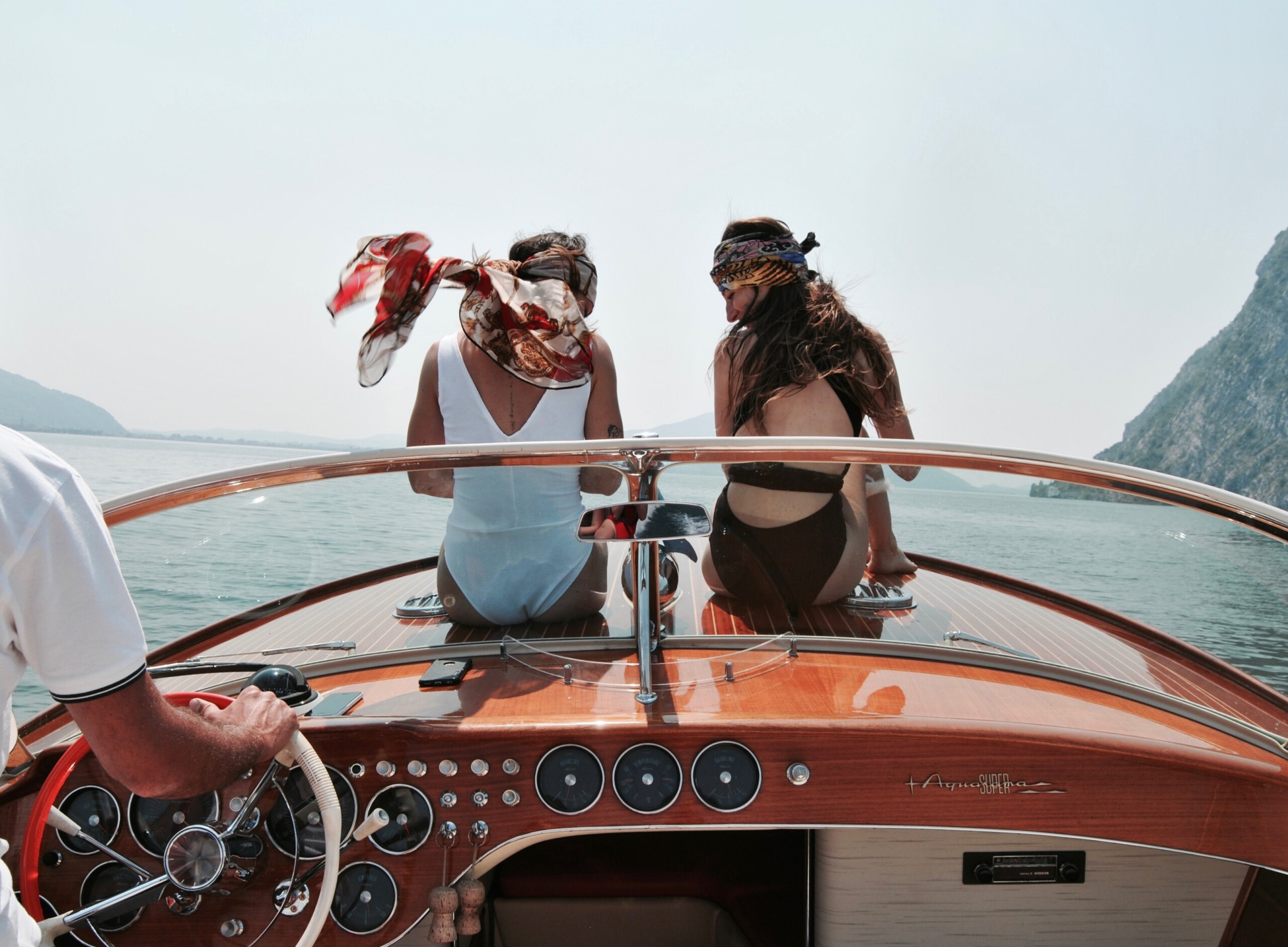 Two women sitting on the bow of a vintage Riva Aquarama Super